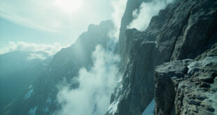 Treacherous cliff edge on Mount Whitney peak shrouded in mist, with steep granite faces and snow at dangerous elevation