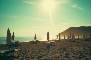 Empty beach chairs and closed umbrellas scattered across a deserted Croatian beach at sunrise with azure waters