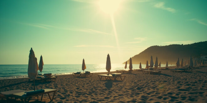 Empty beach chairs and closed umbrellas scattered across a deserted Croatian beach at sunrise with azure waters