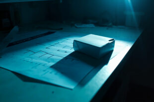 Unopened DNA test kit sitting beside blank family tree chart on laboratory desk with scientific equipment