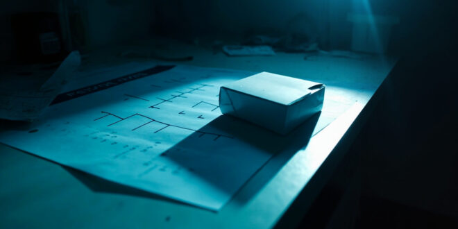 Unopened DNA test kit sitting beside blank family tree chart on laboratory desk with scientific equipment