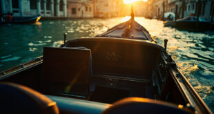 Empty ornate water taxi drifts through deserted Venetian canals at morning, bathed in gold and blue light