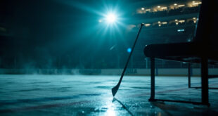 Abandoned hockey stick leaning against empty bench in deserted ice hockey rink at twilight, equipment scattered on ice