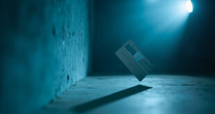 Navy blue credit card suspended mid-air against plain wall in empty home interior, part of viral social media challenge