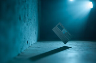 Navy blue credit card suspended mid-air against plain wall in empty home interior, part of viral social media challenge