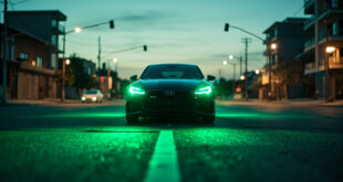 Unoccupied modern vehicle with glowing green front brake lights at a deserted urban intersection during dusk