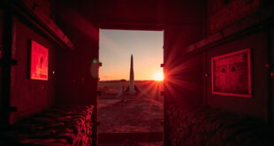 Abandoned ballistic missile standing solitary in dimly lit launch silo at dusk, bathed in red warning lights and gray shadows.
