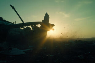 Aircraft wreckage scattered across an empty field at dusk, with a broken wing silhouetted against the darkening sky