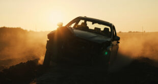 Overturned BMW wreckage lies damaged in an empty rural field at dawn, highlighting aftermath of traffic accident