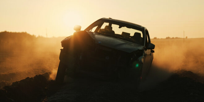 Overturned BMW wreckage lies damaged in an empty rural field at dawn, highlighting aftermath of traffic accident