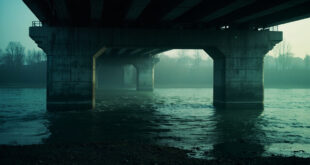 Somber Vltava river flowing under a deserted concrete bridge in Czech Budejovice, captured in dark gray and muted blue tones