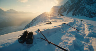 Abandoned hiking gear scattered across a desolate snow-covered mountain ridge at dusk, with an empty trail winding through the terrain.