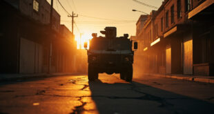 Empty armored military vehicle parked on deserted boulevard in abandoned urban district with closed shops at night