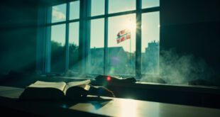 Empty Danish university lecture hall with open books on professor's desk and Danish flag, bathed in Nordic blue light.