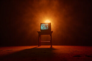 Vintage CRT television displaying memorial tribute sits on wooden table in empty, dimly lit movie theater