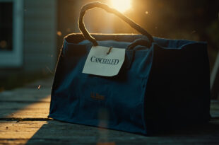 Empty L.L. Bean tote bag with canceled label sits on wooden surface near mailbox, navy and cream colors visible