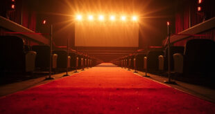 Empty red carpet with festival barriers leading to vacant cinema seats and projection screen at twilight in abandoned film festival venue