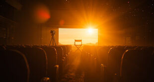 Empty director's chair and vintage camera on tripod in abandoned film studio at dusk, with dark theater seats visible