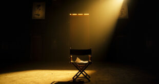 Empty director's chair with script sits under spotlight on dark stage in abandoned movie theater at twilight