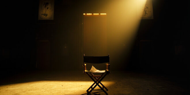 Empty director's chair with script sits under spotlight on dark stage in abandoned movie theater at twilight