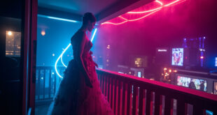 Ornate evening gown on mannequin displayed on empty hotel balcony overlooking film festival crowds below
