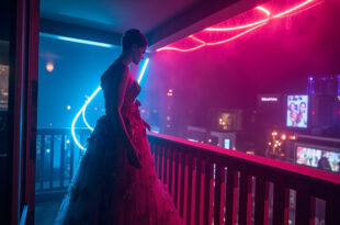 Ornate evening gown on mannequin displayed on empty hotel balcony overlooking film festival crowds below
