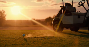 Abandoned golf equipment at golden hour, with clubs leaning against cart and ball on tee on empty emerald green course