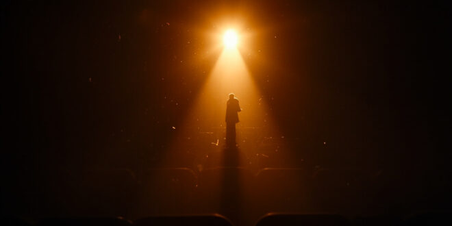 Empty spotlight illuminates a vacant stage in dimmed theater with empty seats, symbolizing an actor's absence