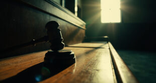 Solitary wooden gavel rests on empty judge's bench in an abandoned courthouse at dawn, symbolizing dormant justice
