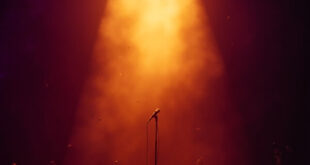 Abandoned microphone stand under golden spotlight on empty concert stage, bathed in deep purple lighting after show