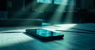 Unattended desk with financial documents and smartphone displaying debt payment interface in sterile government office