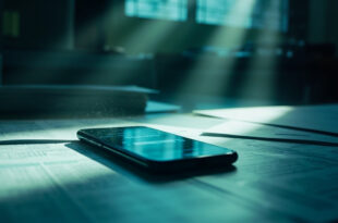 Unattended desk with financial documents and smartphone displaying debt payment interface in sterile government office