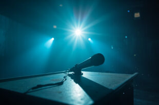 Abandoned television studio at twilight with silent microphone on empty desk, darkened equipment and dust particles