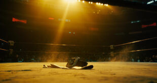 Empty championship belt rests on canvas in a dimly lit, abandoned wrestling ring illuminated by a single spotlight