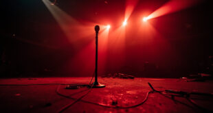 Empty concert hall with abandoned equipment and microphone on a darkened stage bathed in deep red lighting