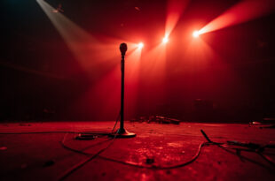 Empty concert hall with abandoned equipment and microphone on a darkened stage bathed in deep red lighting