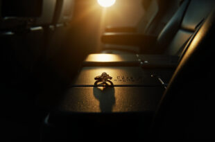 Diamond engagement ring with flight number engraving displayed on airplane tray table between two empty seats