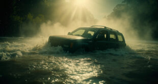 Abandoned vehicle partially submerged in muddy floodwaters of Texas creek during storm