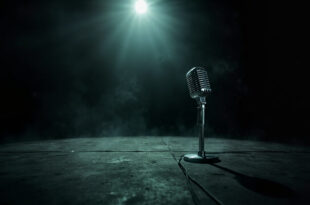 Abandoned vintage microphone stand illuminated by spotlight on empty dark concert stage, symbolizing rock music legacy