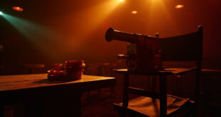 Vintage film camera on director's chair in dimmed empty cinema screening room with film reels on wooden table