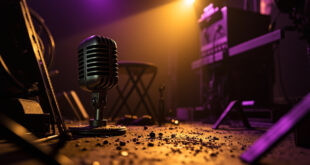 Empty spotlight illuminates vintage microphone and film reel in abandoned recording studio with musical instruments
