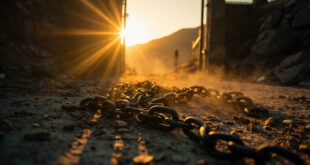 Broken chains and open gate on weathered stone along empty mountain path, bathed in golden light symbolizing freedom