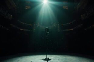 Vintage microphone stand illuminated by a single spotlight on an empty gothic stage in a darkened concert hall