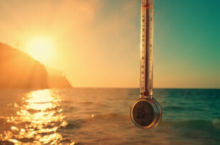 Floating thermometer displaying 29 degrees Celsius over shimmering Mediterranean Sea under scorching midday sun