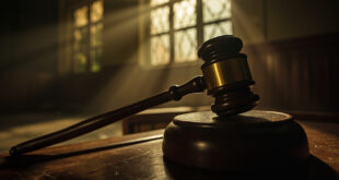 Solitary judge's gavel rests on an empty wooden bench in an abandoned courthouse, illuminated by dramatic light.