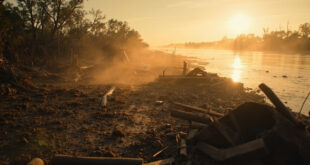 Swollen river recedes leaving muddy debris scattered across flood-damaged Texas riverside area