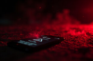 Abandoned smartphone displaying red warning notifications about online sextortion in a dark digital environment