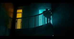 Empty hotel balcony at night with damaged safety barrier, illuminated by contrasting dark blue and yellow lighting
