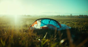Abandoned paraglider equipment lies collapsed in an empty Italian countryside airfield, suggesting a tragic accident.