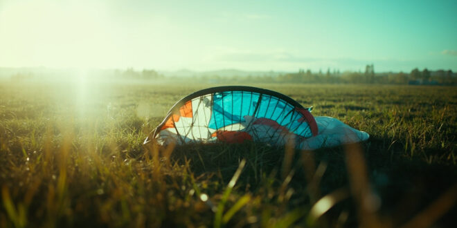 Abandoned paraglider equipment lies collapsed in an empty Italian countryside airfield, suggesting a tragic accident.